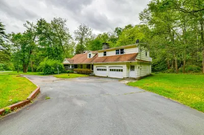 a large white house with a driveway at Serene Duplex with On-Site Brook in Callicoon Center in Roscoe