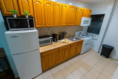 a kitchen with wooden cabinets and a white refrigerator at Hells Kitchen Hideaway in New York
