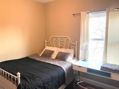 a bedroom with a bed and a desk and a window at Quiet apt only 15 mins from Midtown NYC in Jersey City