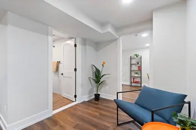 a living room with a blue chair and a hallway at NYC Edge Triplex Full House | Parking & Near Shops in North Bergen