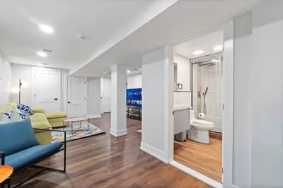 a living room with a blue couch and a bathroom at NYC Edge Triplex Full House | Parking & Near Shops in North Bergen