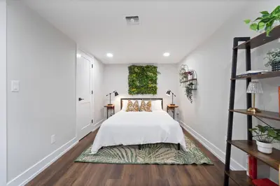 a bedroom with a bed with white walls and wood floors at NYC Edge Triplex Full House | Parking & Near Shops in North Bergen