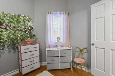 a bedroom with a dresser and a pink chair at Fishtown Fun 2BR Fireplace in Philadelphia