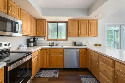 a kitchen with wooden cabinets and a dishwasher at Pocono Escape Style and Serenity in Pocono Pines