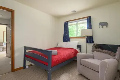 a bedroom with a bed and a chair and a window at Pocono Escape Style and Serenity in Pocono Pines