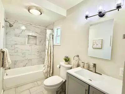 a white bathroom with a sink and a toilet and a tub at Historic Barn View Modern Country Newton House in Newton