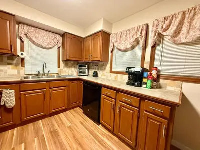 a kitchen with wooden cabinets and wooden floors and windows at Country Comfort Cabin Delaware River Islands in Montague