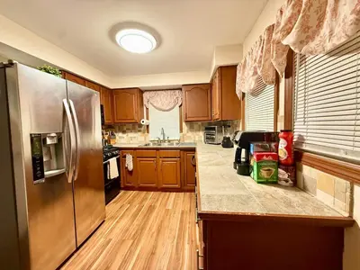 a kitchen with wooden cabinets and a stainless steel refrigerator at Country Comfort Cabin Delaware River Islands in Montague