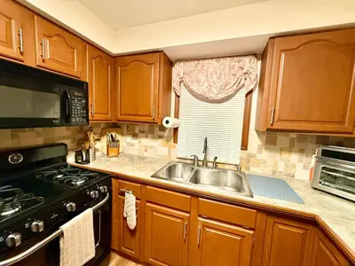 a kitchen with wooden cabinets and a sink and a stove at Country Comfort Cabin Delaware River Islands in Montague