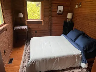 a bedroom with a bed with blue pillows and a window at Starboat Log Home in Jersey Shore
