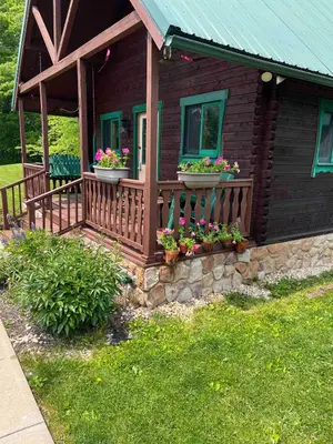 a house with a wooden porch with flowers on it at Starboat Log Home in Jersey Shore