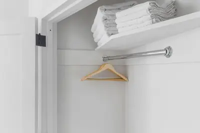 a closet with white towels and a wooden hanger at Blueground Financial District rooftop nr Brooklyn Bridge NYC-1971 in New York