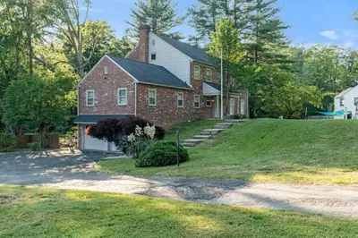 a large brick house on a grassy hill at New Pristine Suburban Escape in Newtown Square