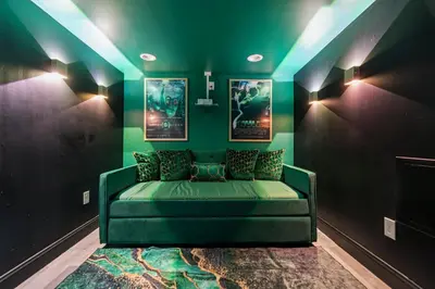 a green couch in a room with two pictures at Chic Urban Oasis Movie Theatre in Philadelphia