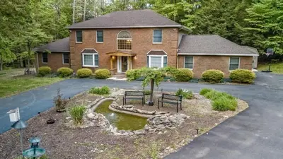a house with two benches in front of a driveway at Heated Private Pool Hot Tub Game Room Sauna in Stroudsburg