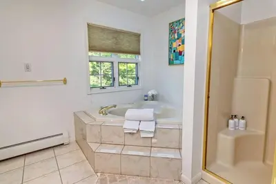 a white bathroom with a tub and a window at Heated Private Pool Hot Tub Game Room Sauna in Stroudsburg