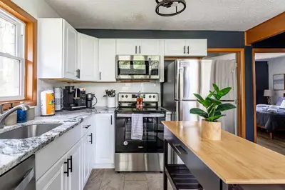 a kitchen with white cabinets and a stainless steel refrigerator at Blue Diamond Hot Tub Fire Pit 3 BDR in Tobyhanna