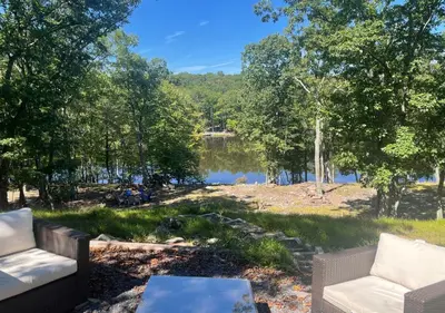 a view of a lake with two couches and a table at Lakefront Kayaks, HotTub FirePit Sauna Pool in East Stroudsburg