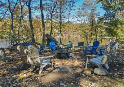 a group of chairs and a table in front of a pond at Lakefront Kayaks, HotTub FirePit Sauna Pool in East Stroudsburg