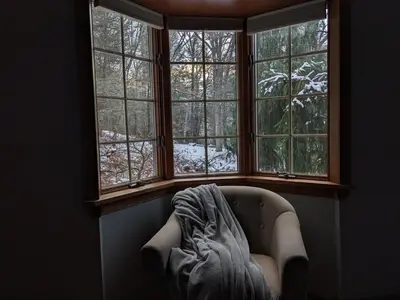 a couch in a room with three windows at Hidden River Lodge at Hawk Mountain