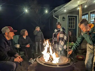 a group of people standing around a fire pit at Hidden River Lodge at Hawk Mountain