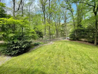 a field of green grass with trees in the background at Hidden River Lodge at Hawk Mountain