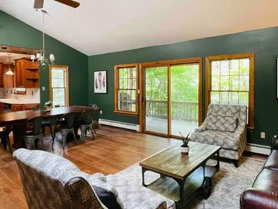 a living room with green walls and a table and chairs at Hidden River Lodge at Hawk Mountain