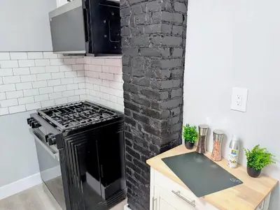 a kitchen with a stove and a black brick wall at Newly renovated luxury 3BR Condo! 30 mins to NYC in Jersey City