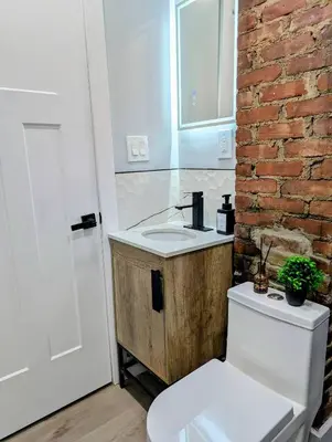 a bathroom with a sink and a toilet and a brick wall at Newly renovated luxury 3BR Condo! 30 mins to NYC in Jersey City