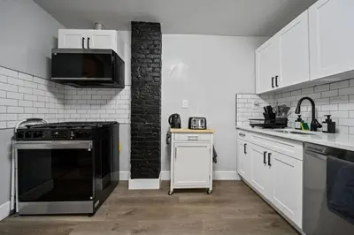 a kitchen with white cabinets and a black stove at Newly renovated luxury 3BR Condo! 30 mins to NYC in Jersey City