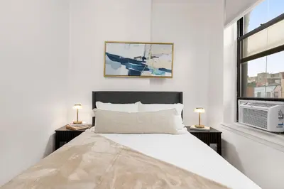 a white bedroom with a bed and two night stands at Chic East Village Retreat Comfort in Heart of NYC in New York