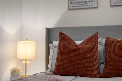 a bed with two brown pillows and a lamp at Chic East Village Retreat Comfort in Heart of NYC in New York