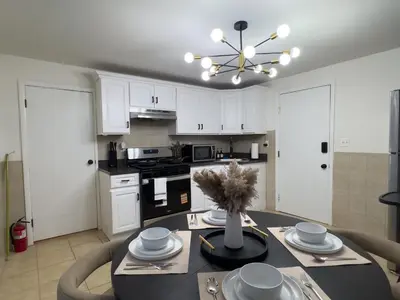 a kitchen with white cabinets and a dining room table at Elegant NYC View Stay Park Free 6 beds Sleep 8 in Kearny
