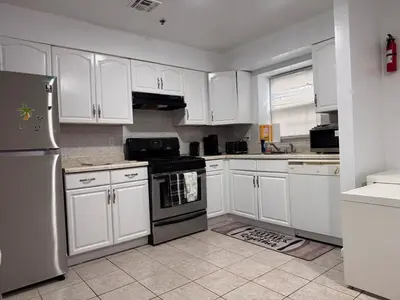 a kitchen with white cabinets and a stainless steel refrigerator at Large 2Kings 2 bedroom 2 bath by EWR NYC Downtown Newark in Newark