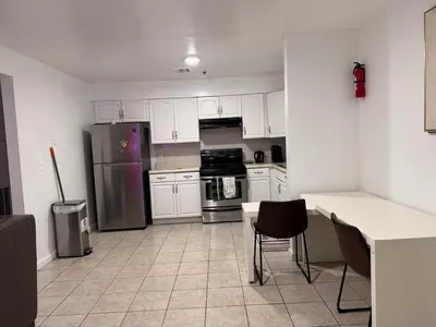 a kitchen with white cabinets and a stainless steel refrigerator at Large 2Kings 2 bedroom 2 bath by EWR NYC Downtown Newark in Newark