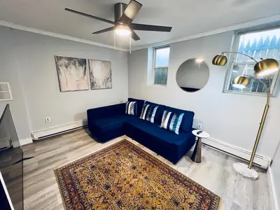 a living room with a blue couch and a ceiling fan at Renovated private urban flat - 20 min to Manhattan NYC in Jersey City