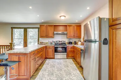a kitchen with wooden cabinets and a stainless steel refrigerator at Walk to River Couples Retreat in Kintnersville! in Kintnersville