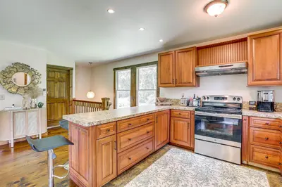 a kitchen with wooden cabinets and a stove top oven at Walk to River Couples Retreat in Kintnersville! in Kintnersville