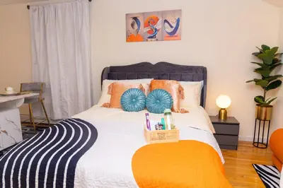 a bedroom with a bed with orange and blue pillows at Luxury Vibes ,Cozy Location in East Orange