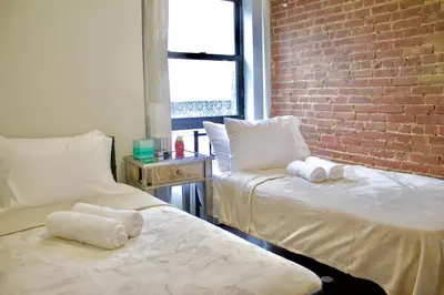 two beds in a room with a brick wall at Stay In Times Square! 2-Bedroom Apartments in New York