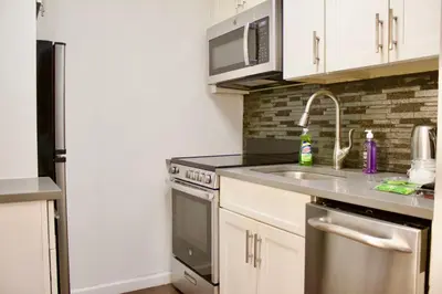 a kitchen with a sink and a refrigerator at Stay In Times Square! 2-Bedroom Apartments in New York