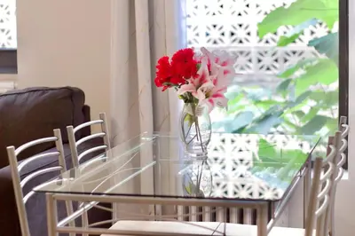 a vase of flowers on a glass table with two chairs at Stay In Times Square! 2-Bedroom Apartments in New York