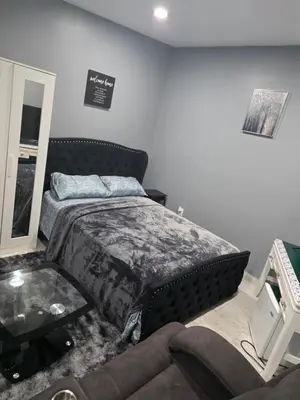 a bedroom with a bed and a couch at A newly built detached studio apartment with queen size bed in Irvington