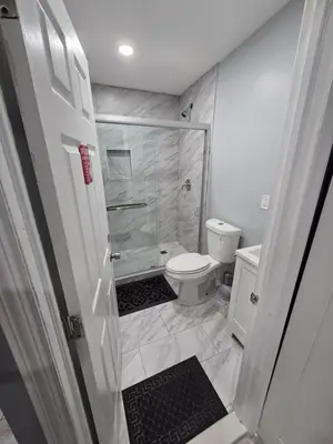 a white bathroom with a shower and a toilet at A newly built detached studio apartment with queen size bed in Irvington