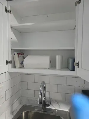 a kitchen with a sink and a shelf with towels at A newly built detached studio apartment with queen size bed in Irvington
