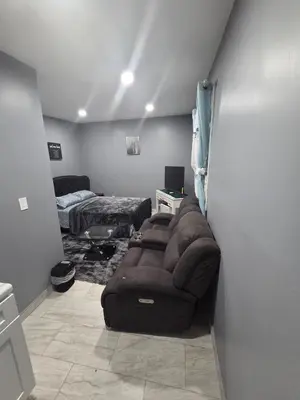 a living room with a couch and a bed at A newly built detached studio apartment with queen size bed in Irvington
