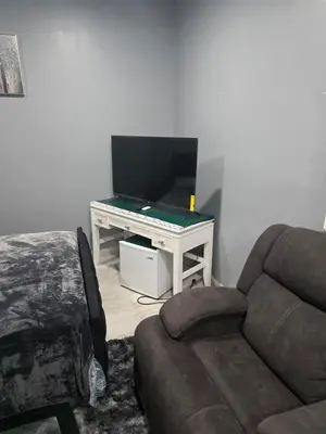 a living room with a couch and a flat screen tv at A newly built detached studio apartment with queen size bed in Irvington