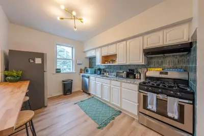 a kitchen with white cabinets and a stove top oven at Stylish 2 BD Apt-18 mins from NYC-Steps away Bus stop, Restaurants, Groceries in Jersey City