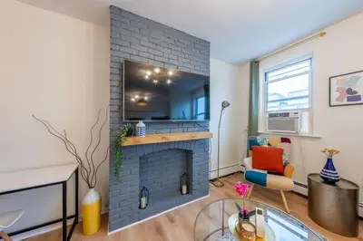 a living room with a brick fireplace with a tv at Stylish 2 BD Apt-18 mins from NYC-Steps away Bus stop, Restaurants, Groceries in Jersey City