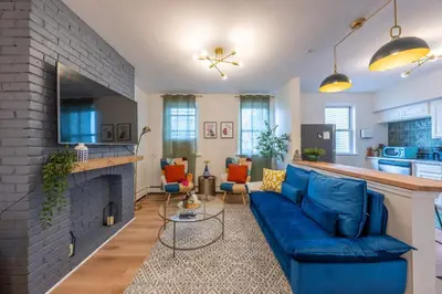 a living room with a blue couch and a fireplace at Stylish 2 BD Apt-18 mins from NYC-Steps away Bus stop, Restaurants, Groceries in Jersey City